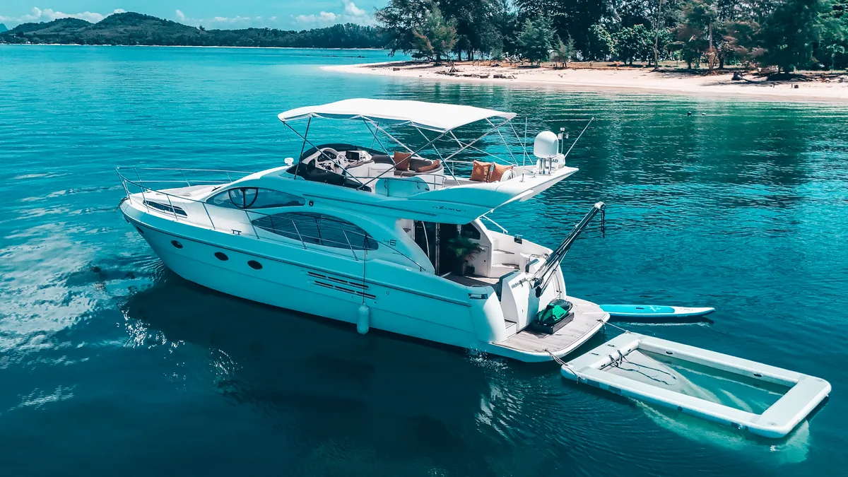 Azimut 46 Aqua Mas — aerial view at anchor in turquoise water beside a sandy bay