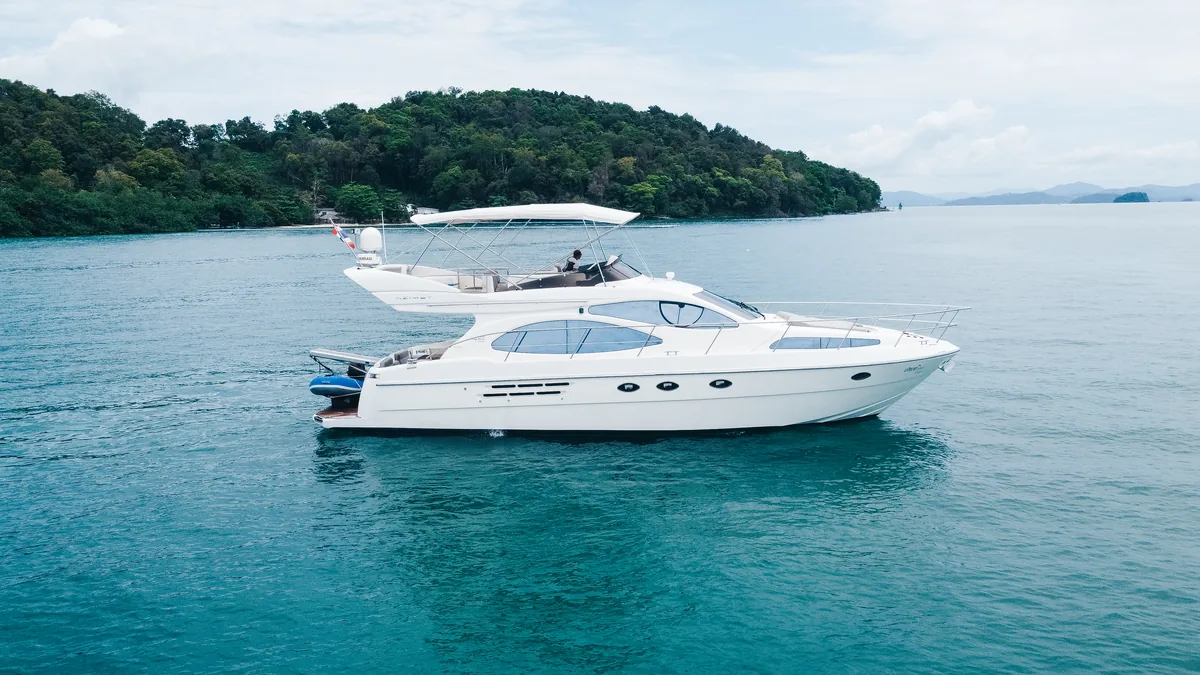 Azimut 46 Aqua Mas — at anchor beside a forested limestone island